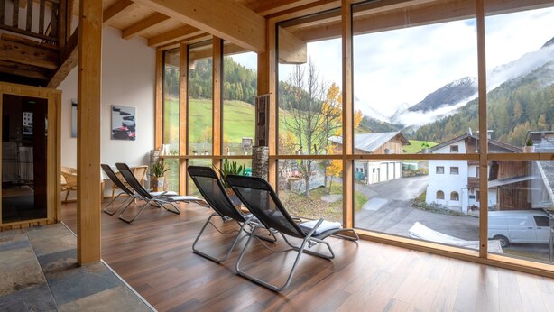 A spacious room with large windows, wooden beams, and a view of a mountain landscape. - Ambiente by Interhome (Umhausen)