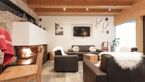 A cozy living room with a fireplace, leather sofas, a TV, and a stone floor. - Ambiente by Interhome (Umhausen)