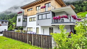 A modern two-story building with balconies, surrounded by lush greenery and a mountainous backdrop. - Ambiente by Interhome (Umhausen)