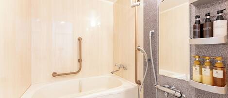 A modern bathroom with a bathtub, grab bars, a shower, and a shelf with toiletries.