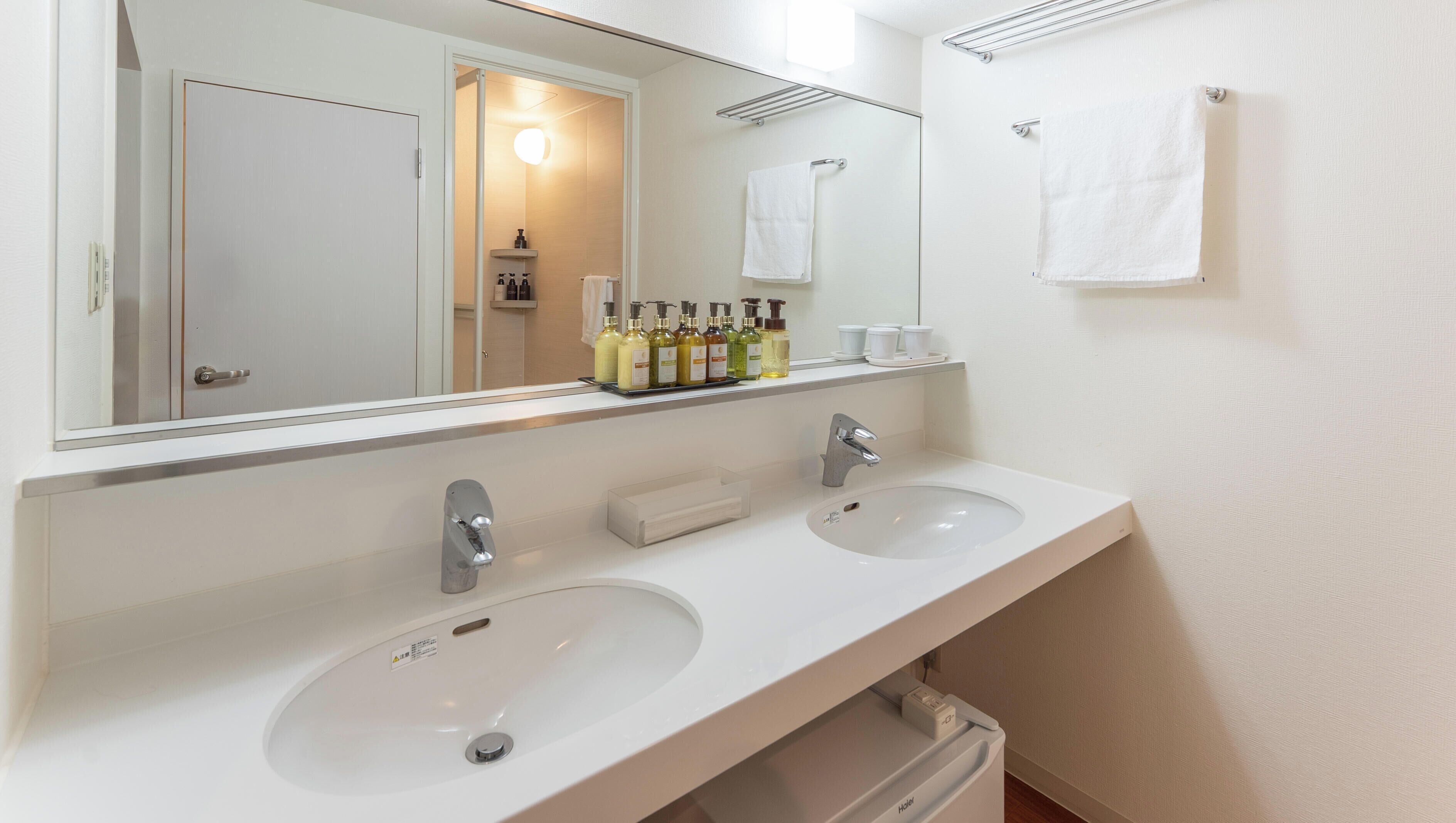 Een moderne badkamer met twee wastafels, een grote spiegel en een handdoekrek.