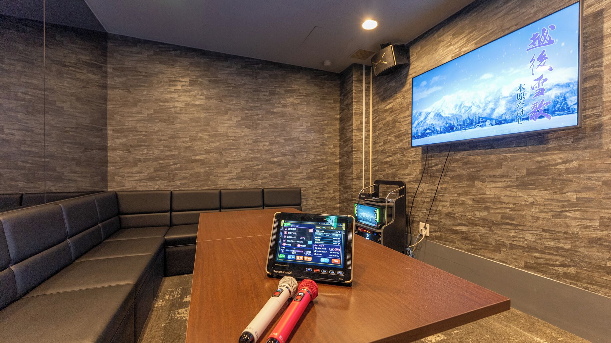 A modern cinema room with a large screen, a laptop, and a microphone on a wooden table.