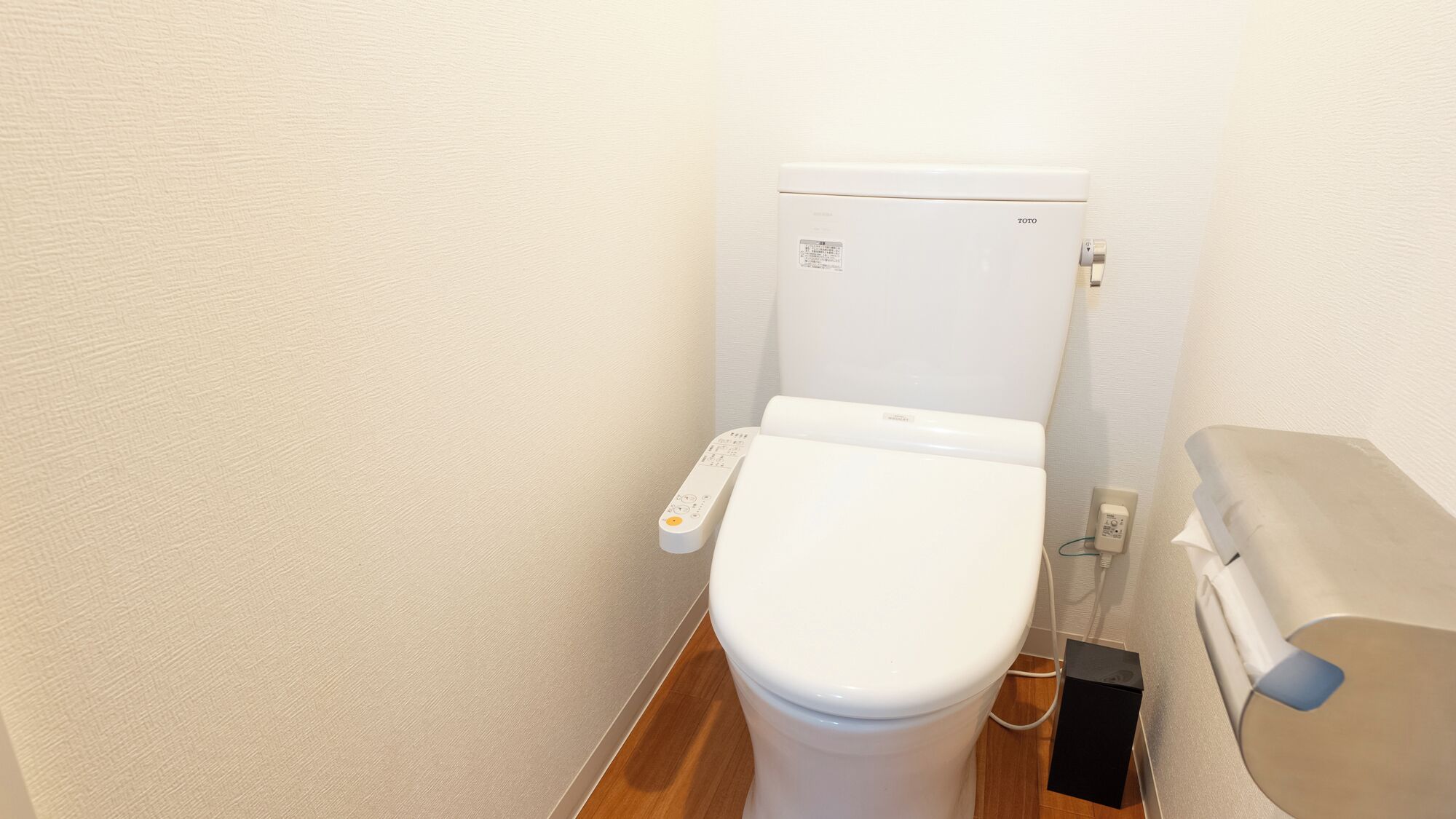 A white toilet with a control panel and a bidet attachment.