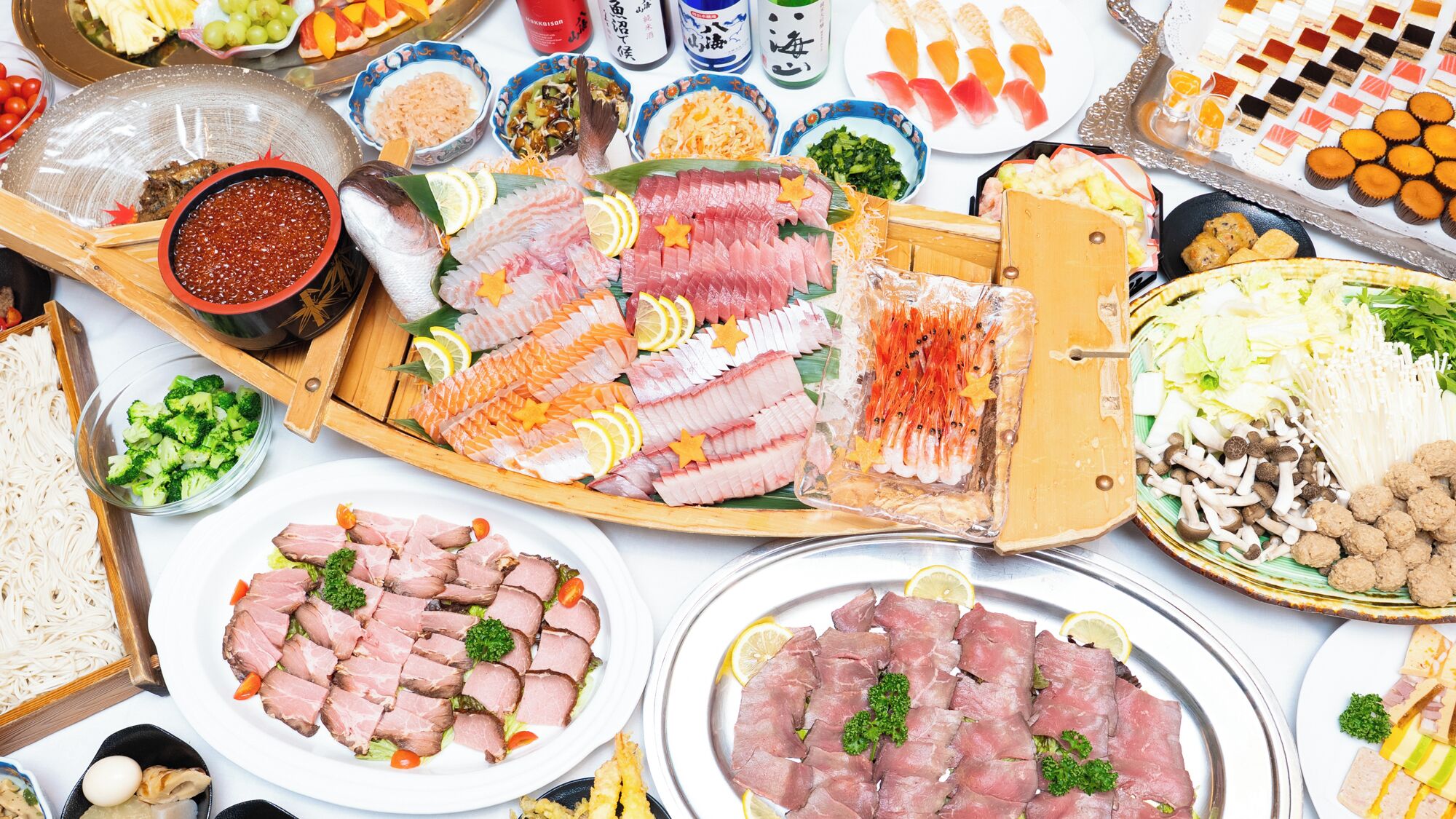 A variety of food items including sushi, sashimi, and other dishes, arranged on a table.