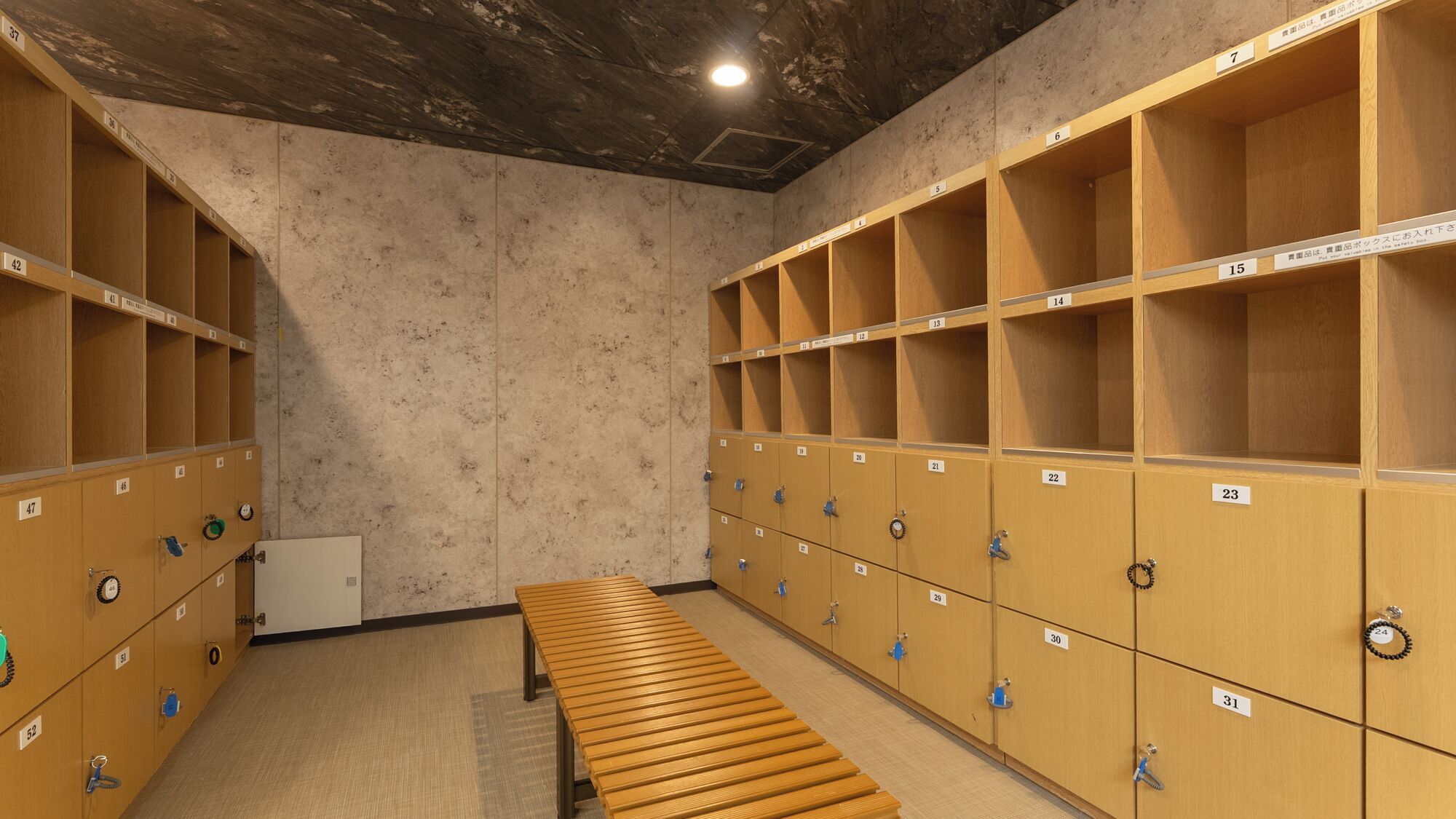 A locker room with multiple wooden lockers, numbered from 1 to 31, and a wooden bench in the center.