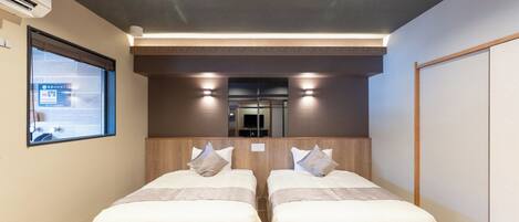 Une chambre d’hôtel avec deux lits, une fenêtre et un miroir.