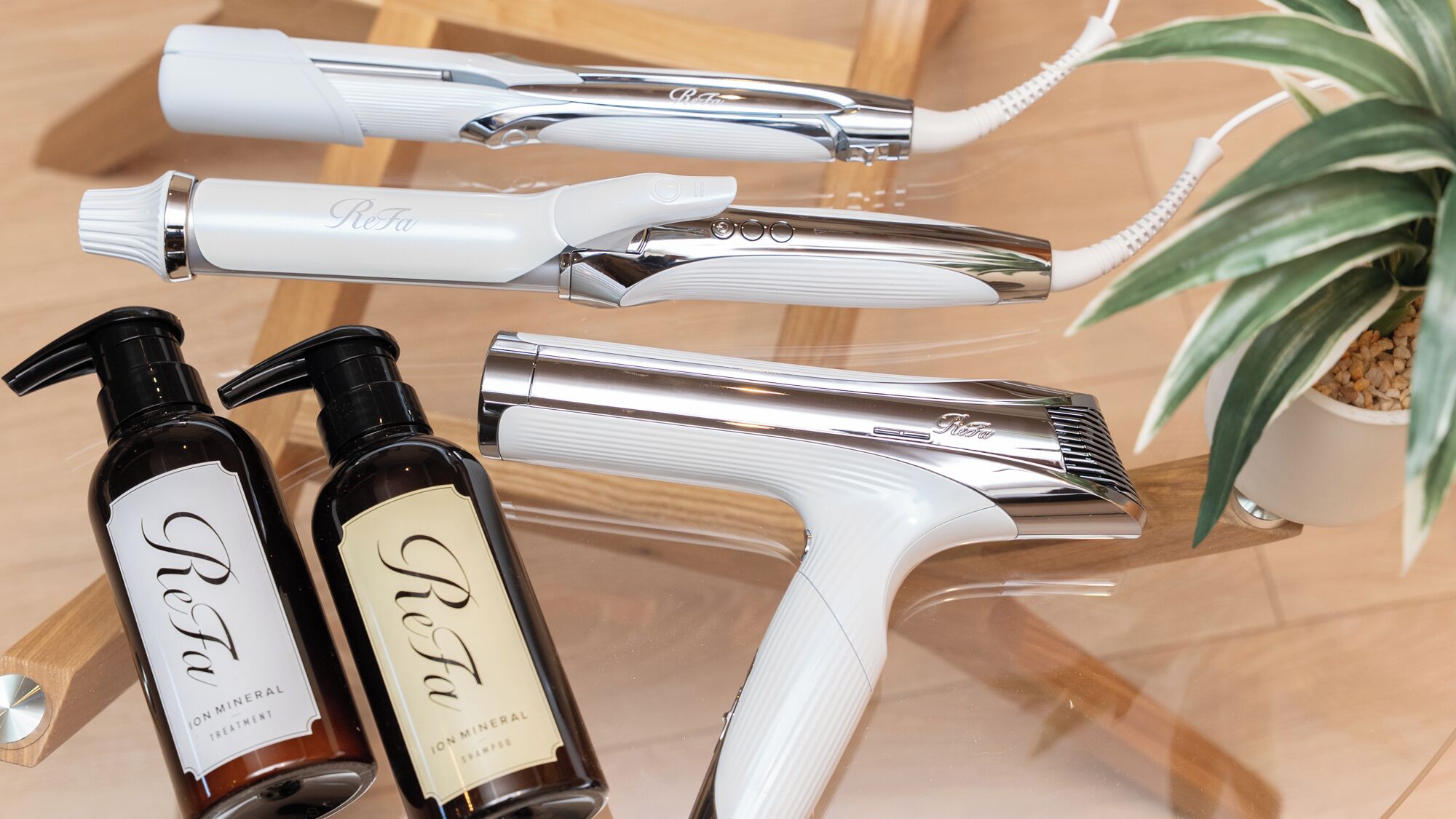 Une salle de bain équipée d’un robinet chromé, d’une douchette blanche et de deux flacons de produits de soin minéraux ReFa.