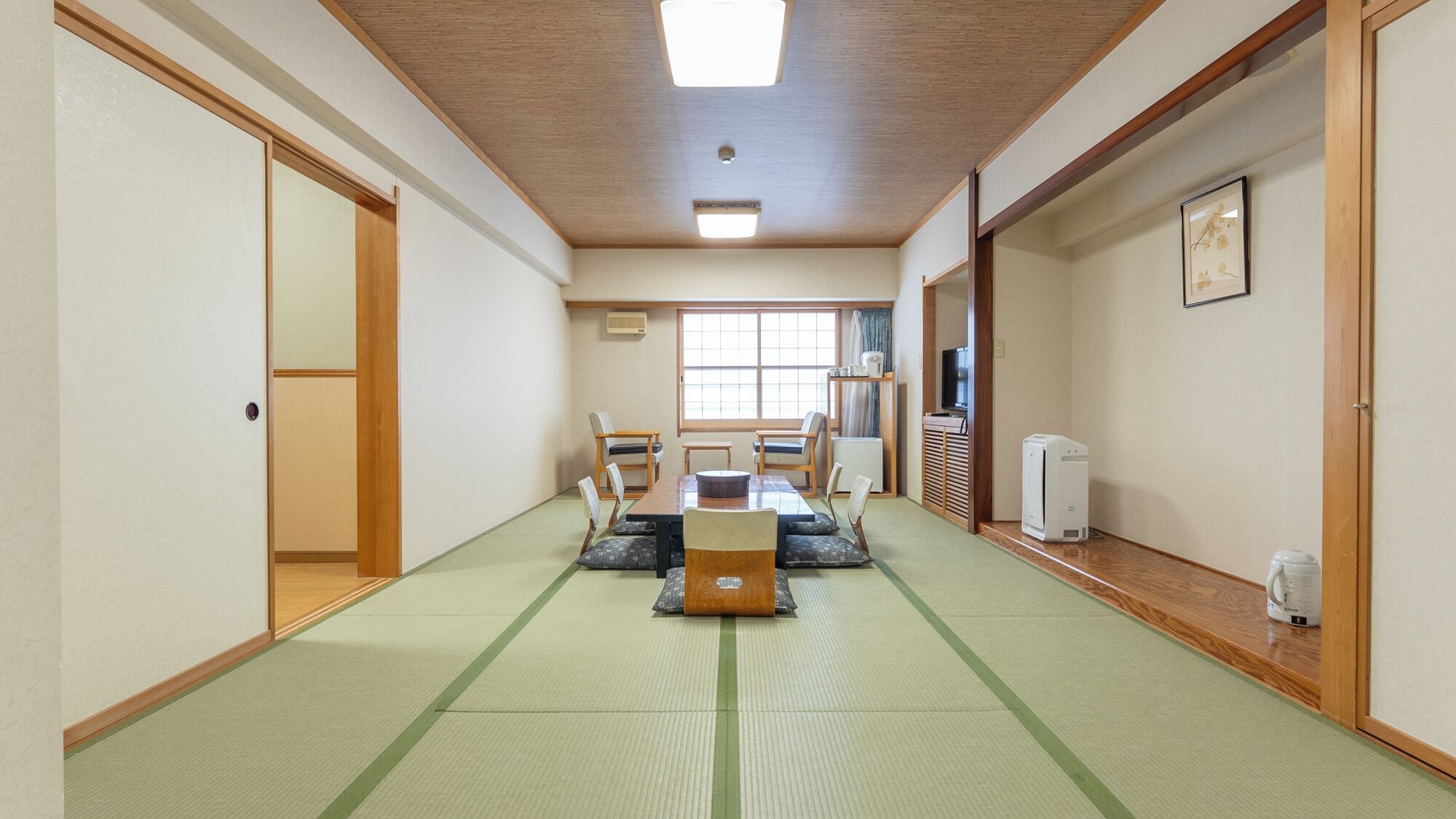 A traditional Japanese room with tatami flooring, a low table with cushions, and sliding doors.