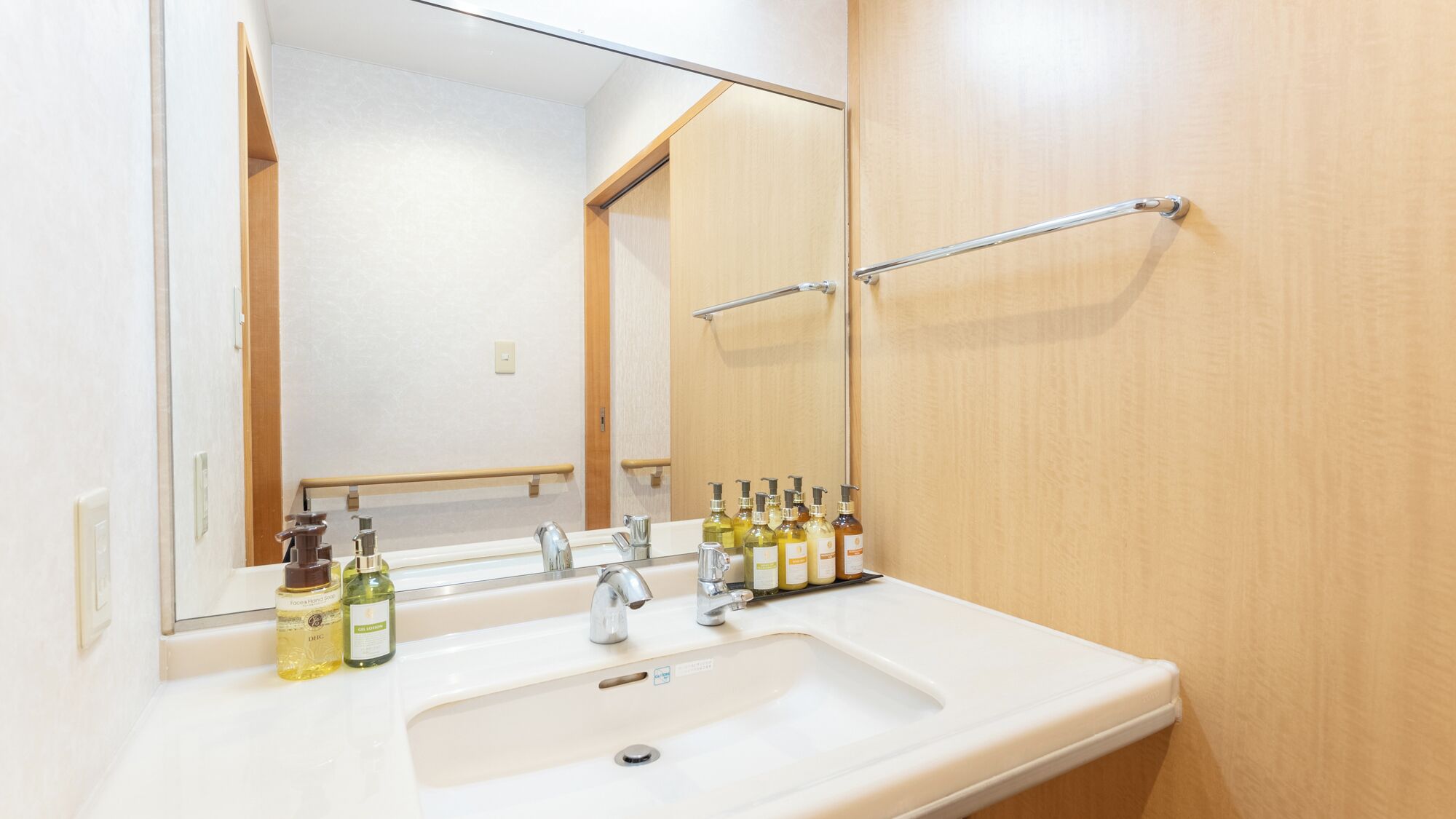 Un baño con un lavabo blanco, dos llaves, un espejo y una puerta de madera.