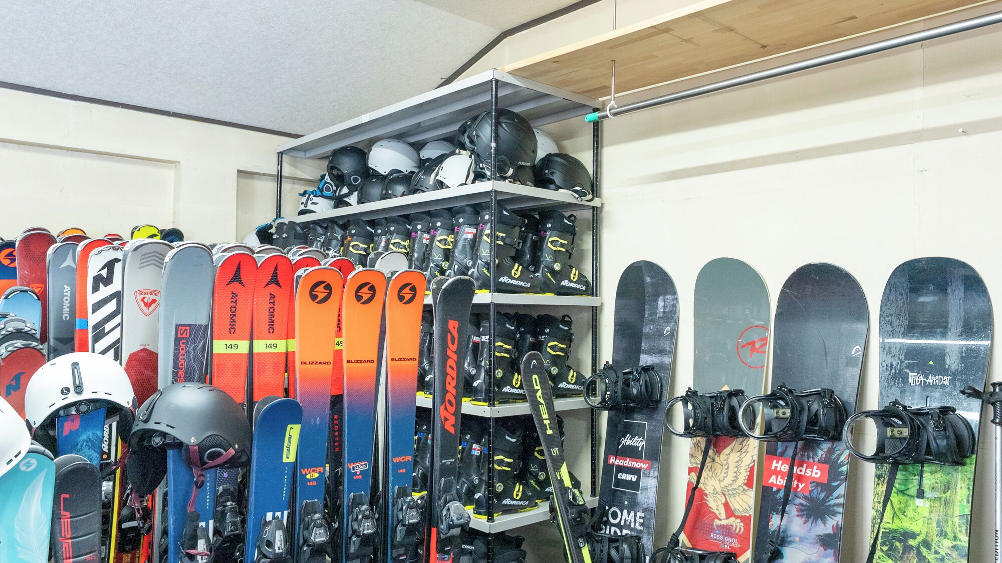 A storage room with skis and helmets organized on shelves.
