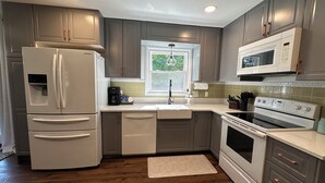 A kitchen with a refrigerator, microwave, oven, and sink.