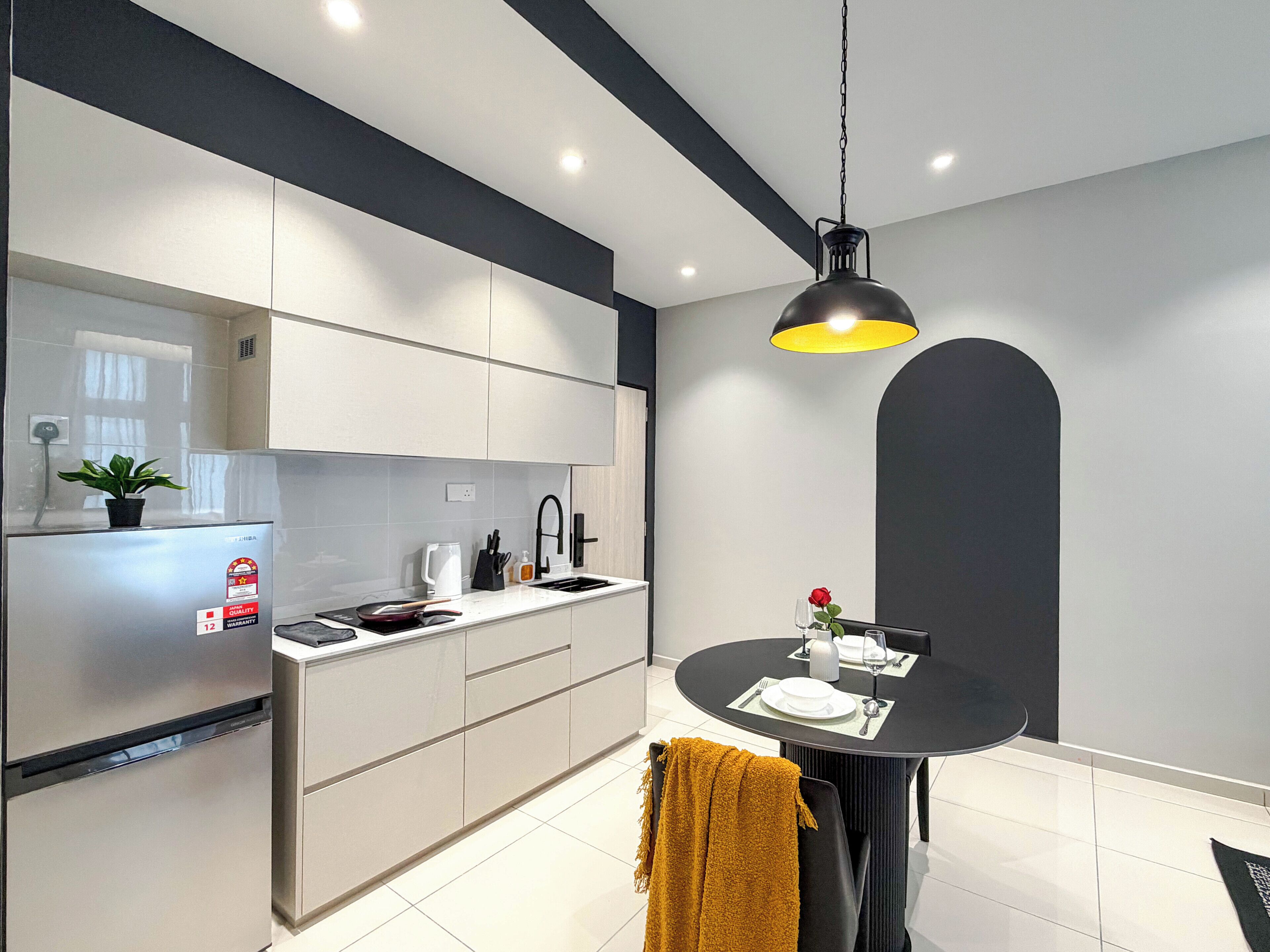 Een moderne keuken met witte kastjes, een zwart aanrecht en een eethoek met een ronde tafel.