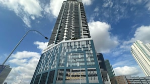 Un moderno edificio de gran altura con un llamativo letrero 'SPACE RESIDENCY', fachada de vidrio y un diseño vertical estructurado.
