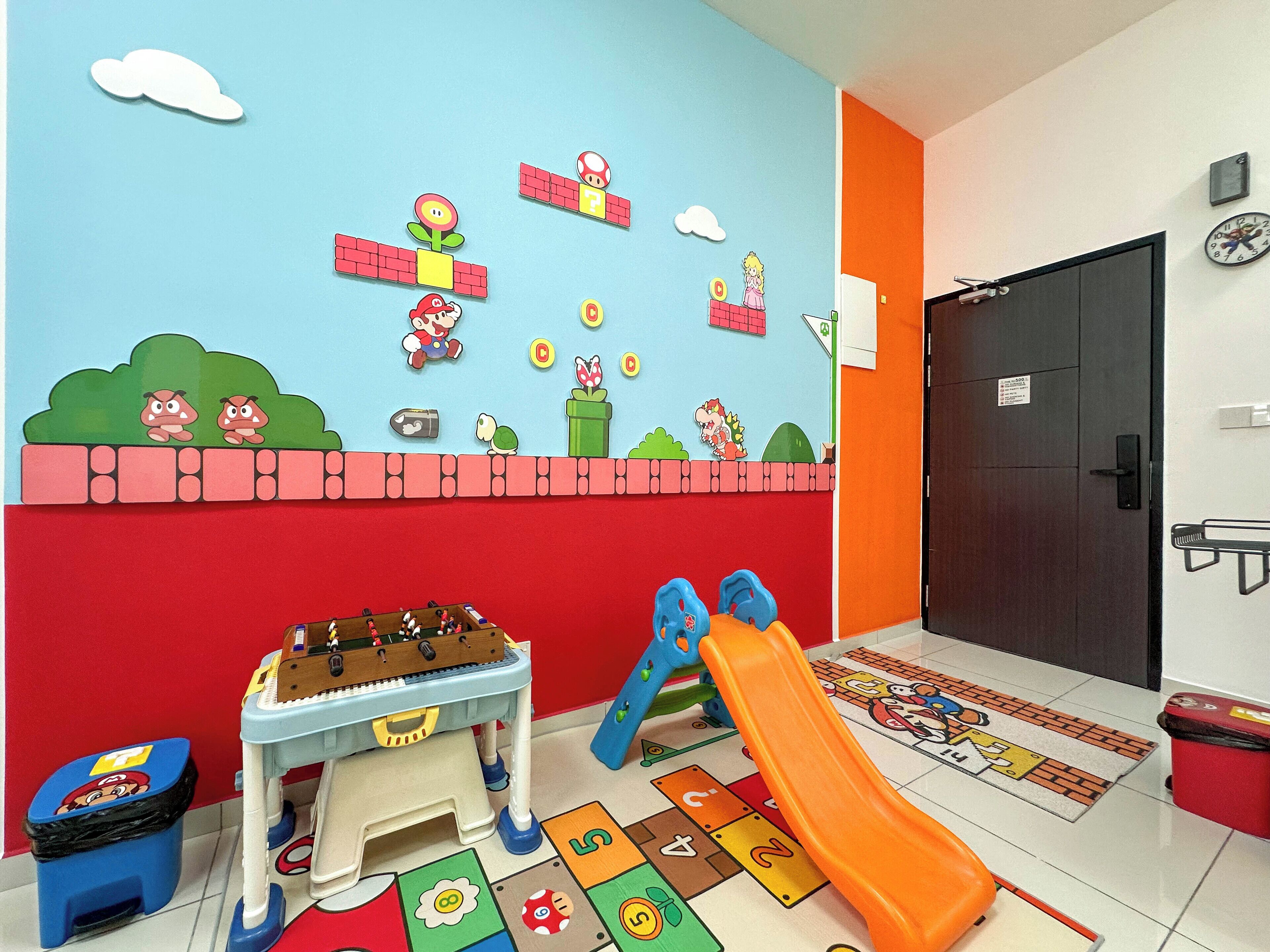 A children's play area with a Mario-themed wall, a small table with toys, and a slide.