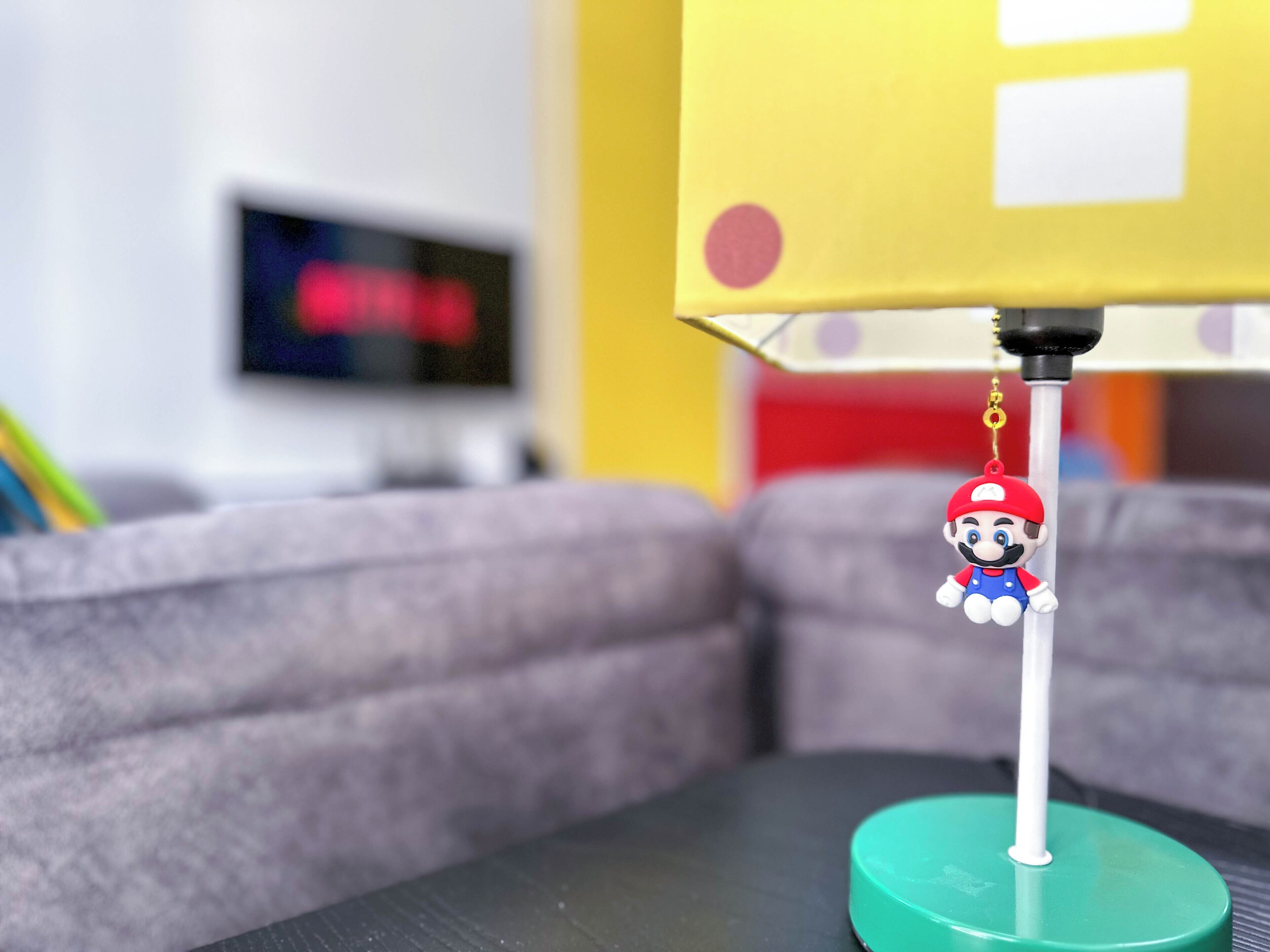 A Mario keychain hanging from a lamp on a table.