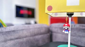 A Mario keychain hanging from a lamp on a table.