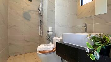 A modern bathroom with a shower, toilet, and sink.