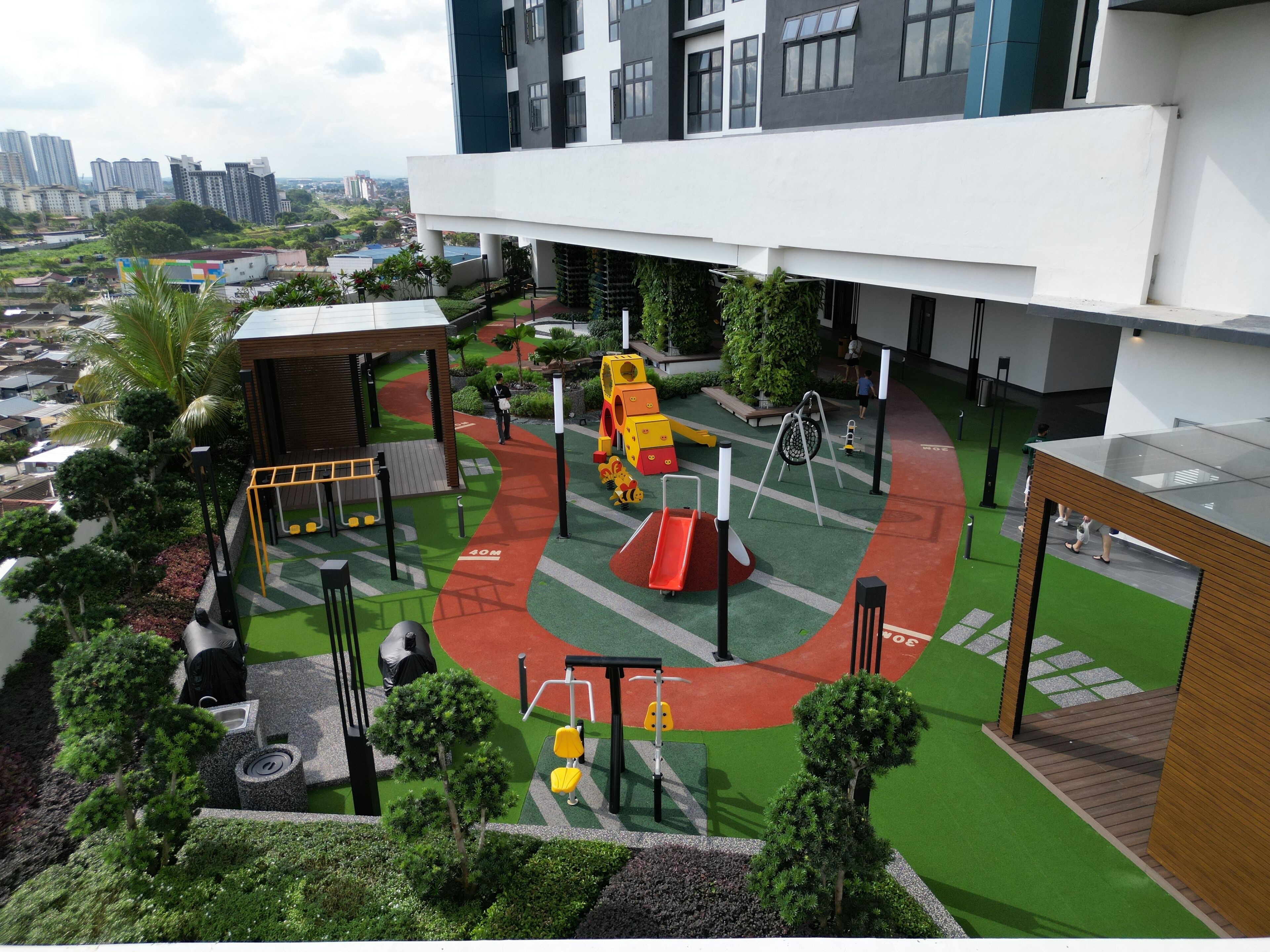 A playground with various play equipment, surrounded by greenery and a building with a modern design.