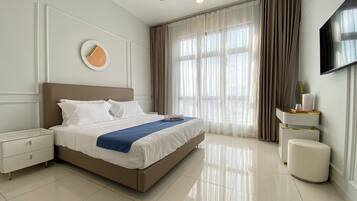 A modern hotel room with a large bed, a bedside table, a small bedside table, a mirror, and a TV mounted on the wall.