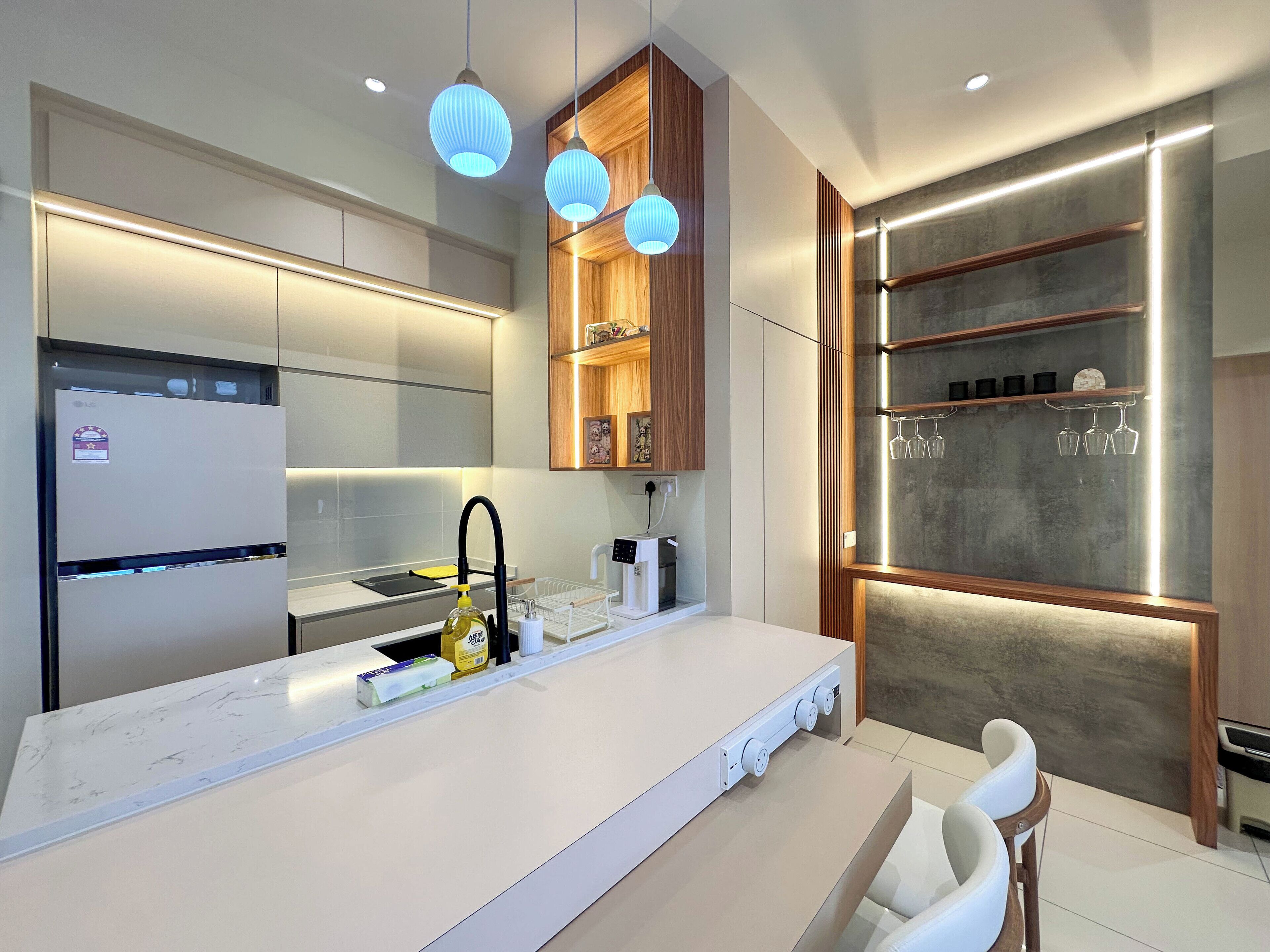 A modern kitchen with a white countertop, built-in appliances, and pendant lighting.