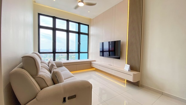 Un salón moderno con un sofá, un televisor de pantalla plana montado en la pared y un amplio ventanal con vistas a la ciudad.