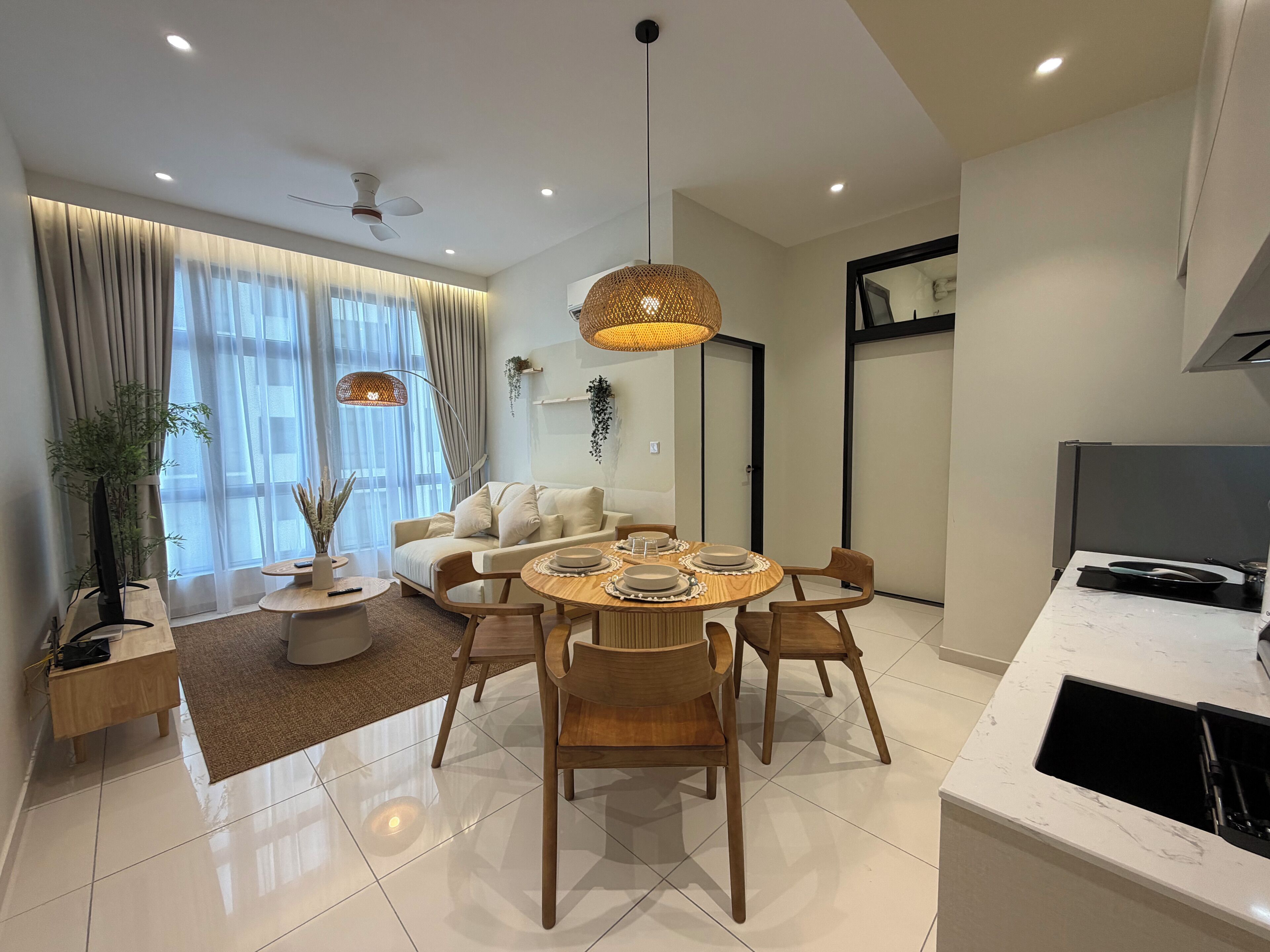 Una sala de estar moderna con comedor, ventilador de techo, ventana grande con cortinas y cocina con lavamanos.