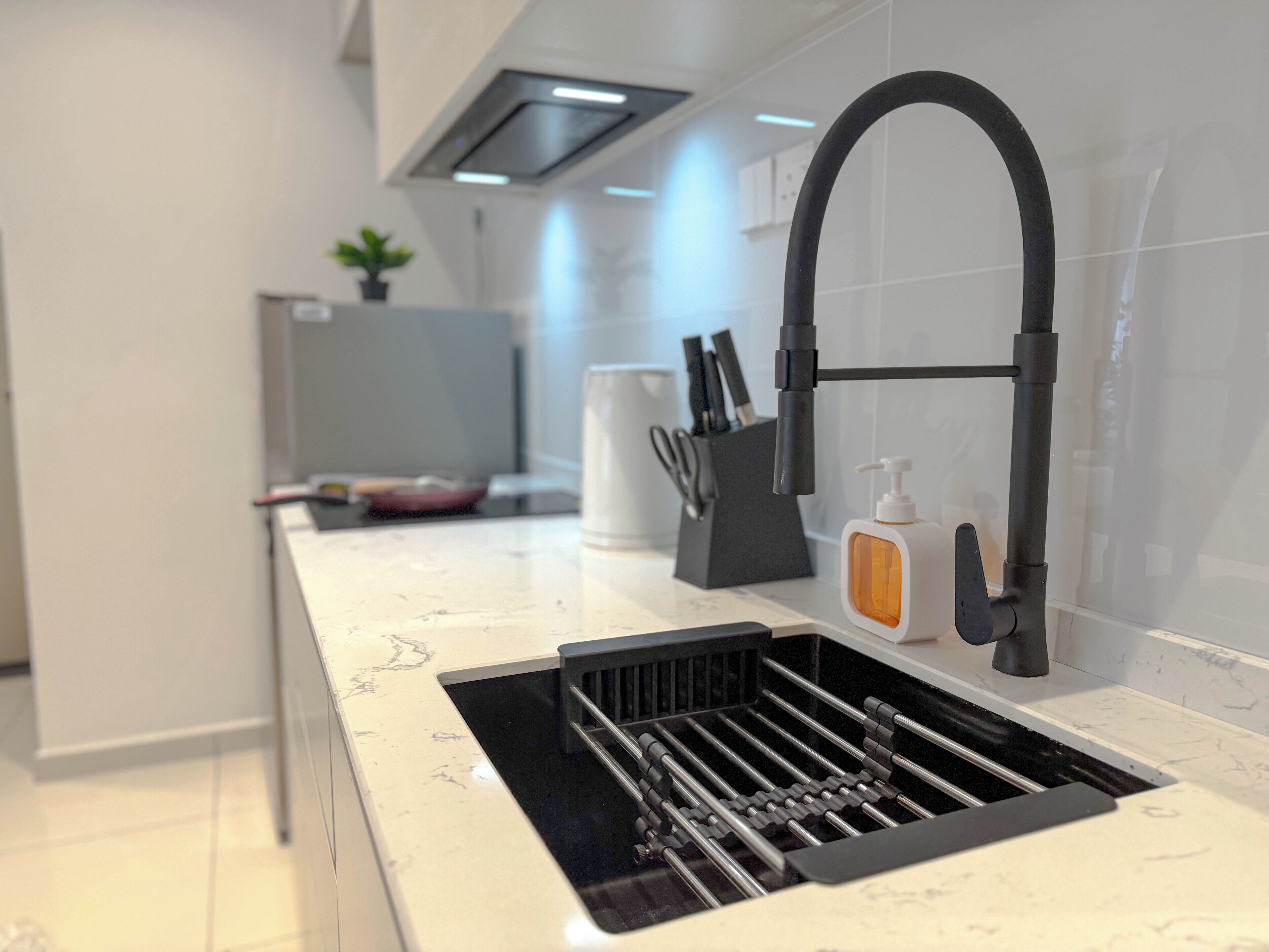 A modern kitchen with a black faucet, a built-in sink, and a countertop with a soap dispenser.
