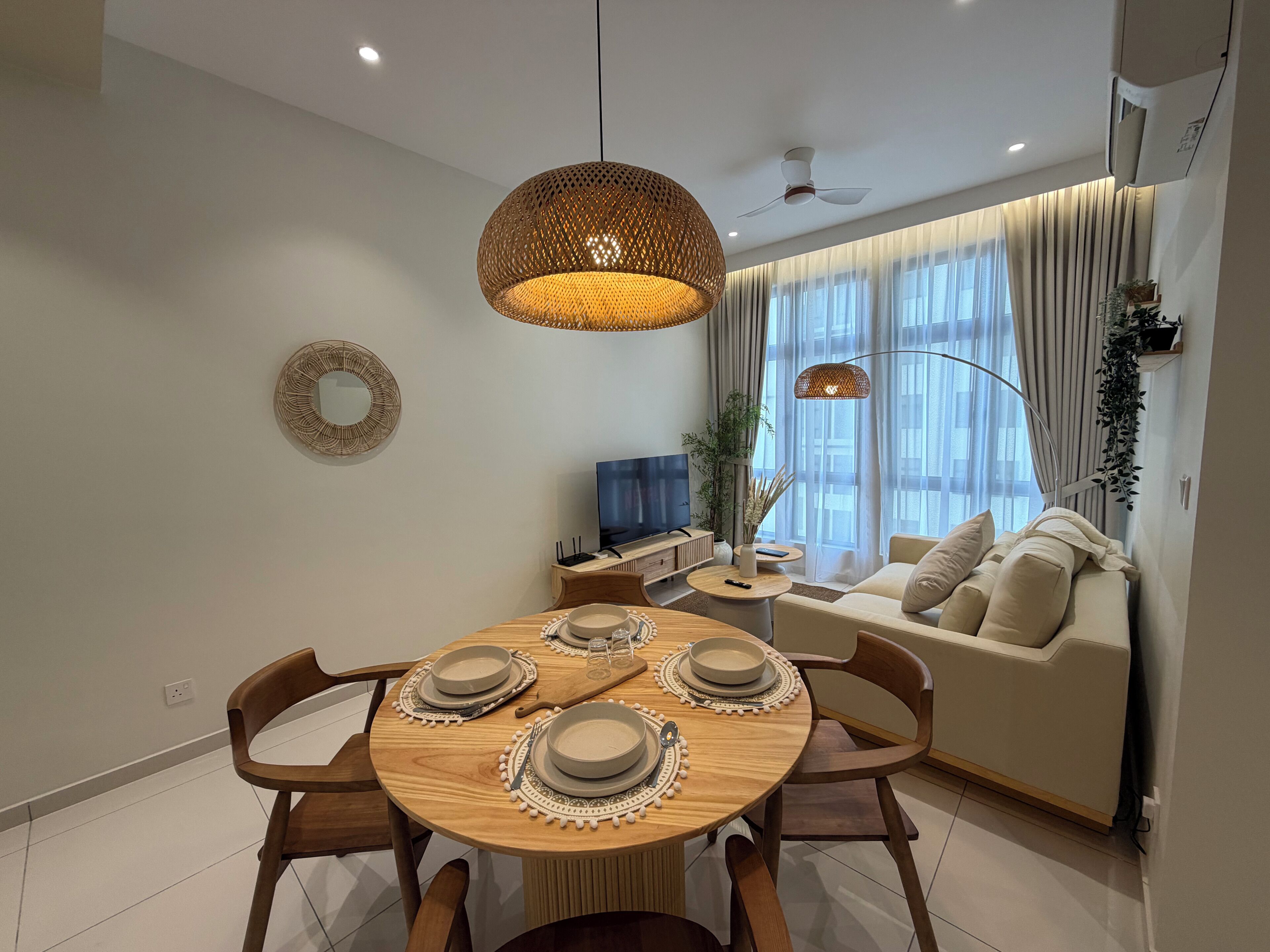 Una sala de estar moderna con comedor, un conjunto de sofás, un televisor y un ventilador de techo.