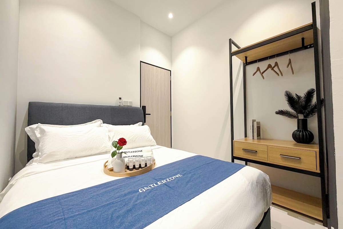 Un lit bien fait, avec une couverture bleue, des oreillers blancs et un plateau contenant des articles de toilette.