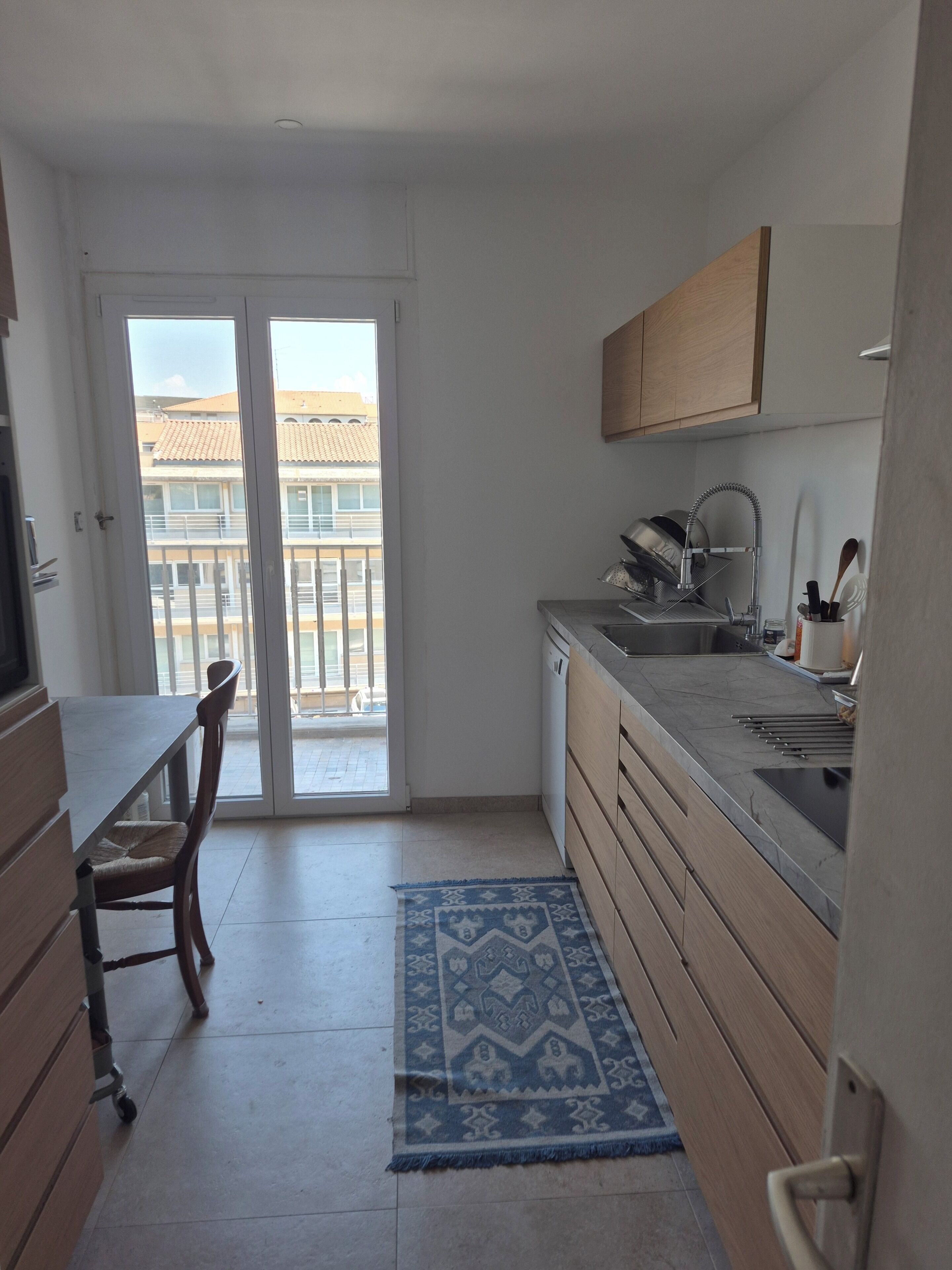 Eine kleine Küche mit Esstisch, Spüle und Blick auf den Balkon.