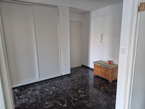 A room with a wardrobe, a wooden dresser, and a door.