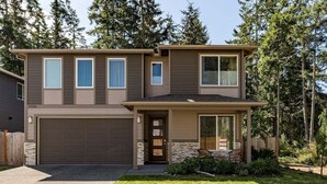 A two-story house with a garage, a front porch, and a well-maintained lawn. - Perch - Modern End-Unit Surrounded by Nature (Oak Harbor)