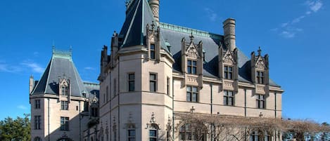 Ein großes, historisches Gebäude mit mehreren Türmen und einer markanten Treppe, die zum Eingang führt.
