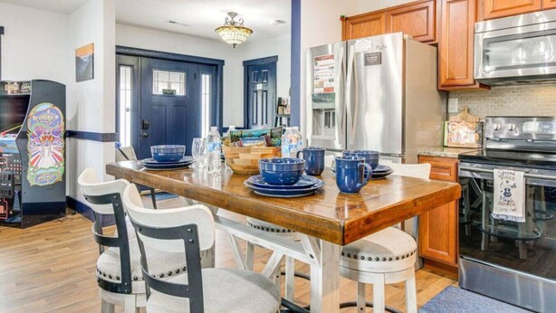 A modern kitchen with wooden cabinets, stainless steel appliances, and a dining area with blue tableware.