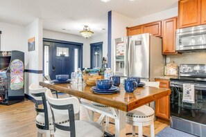 Een moderne keuken met houten kastjes, roestvrijstalen apparatuur en een eethoek met blauw servies.
