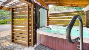 A wooden cabin with a hot tub, wooden walls, and a covered entrance.