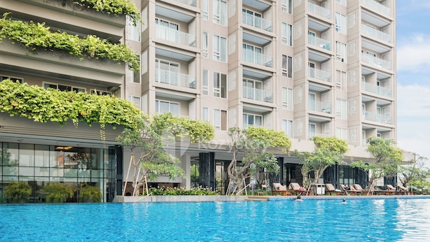 A modern hotel with a swimming pool, outdoor seating, and lush greenery. - Kawari by Kozystay - Paskal (Bandung)