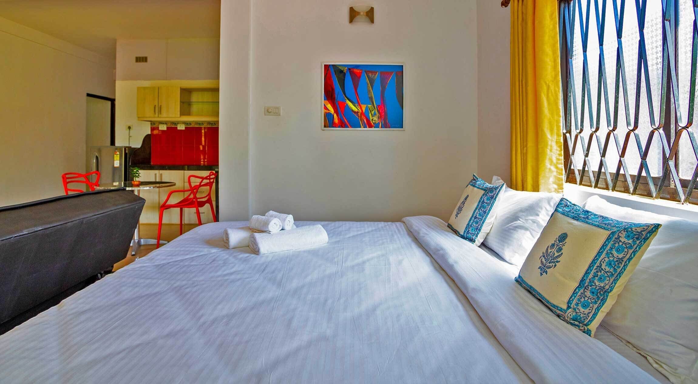Una habitación de hotel con una cama, un cuadro en la pared y vistas al exterior.