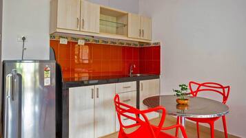 A compact kitchen with a refrigerator, cabinets, and a dining area with a table and chairs.
