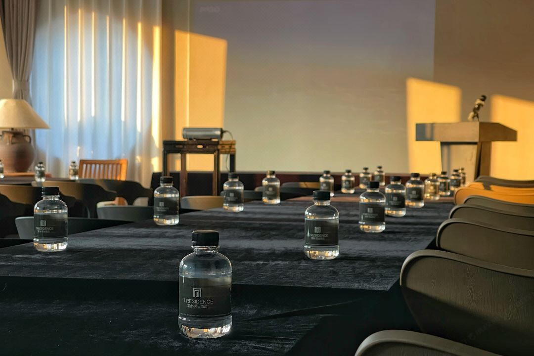 A conference room with a long table set up with water bottles labeled "TRESIDENCE."