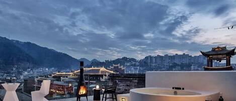 Terraza en la azotea con una chimenea, zona de estar y vistas a un paisaje urbano y arquitectura tradicional.
