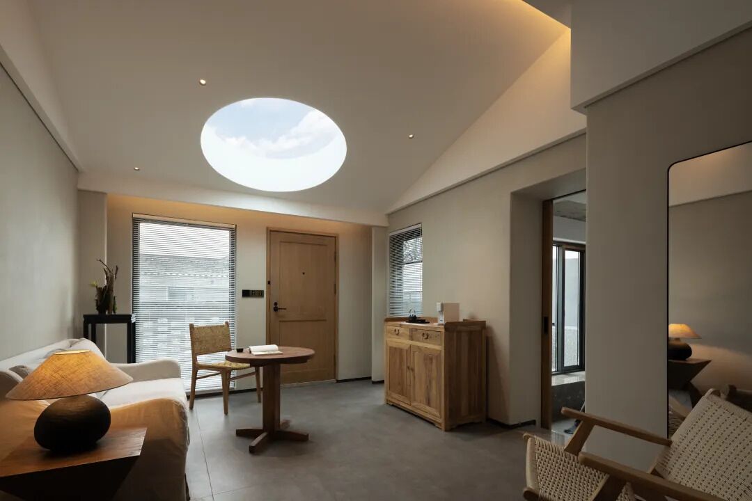 A modern living room with a skylight, a sofa, a dining table, and a kitchen area.