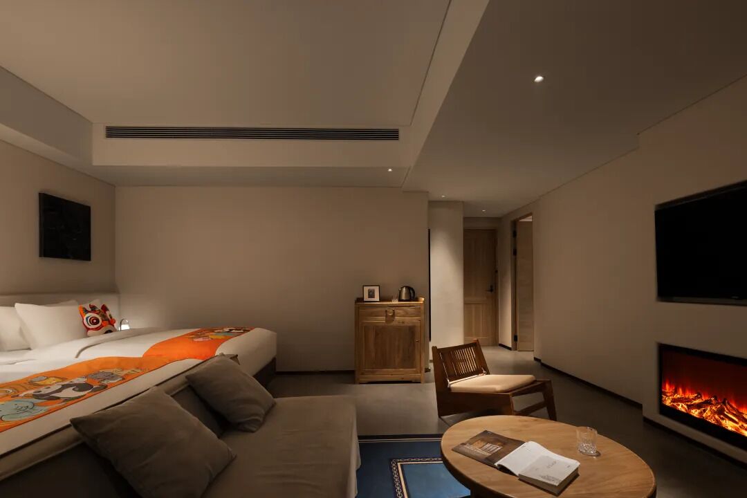 Et moderne hotelværelse med en seng, en sofa, et lille bord, et fjernsyn og en pejs.
