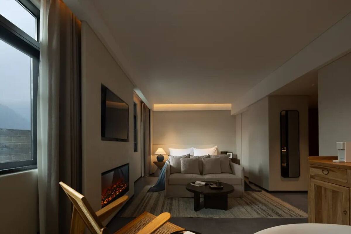 A modern hotel room with a sofa, coffee table, and a fireplace.