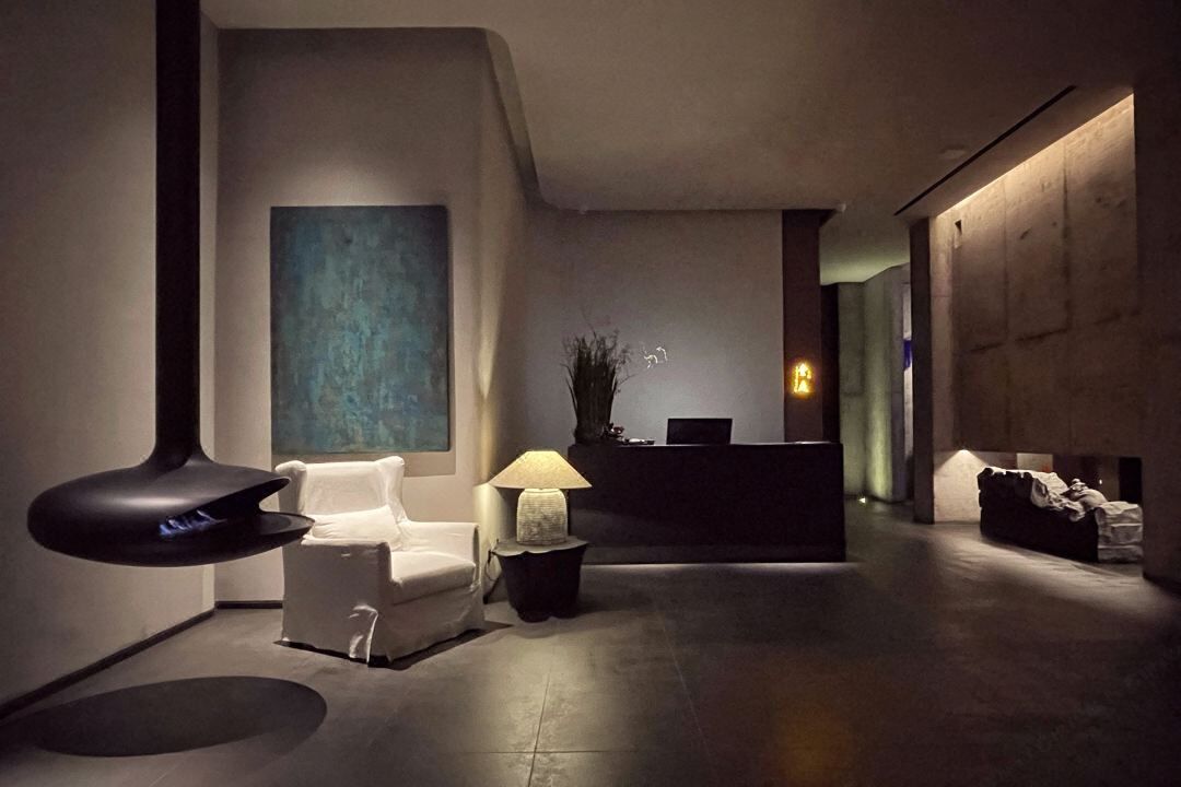 Un hall d’entrée moderne avec un comptoir d’accueil, un canapé blanc, une lampe sur pied et un grand tableau abstrait accroché au mur.