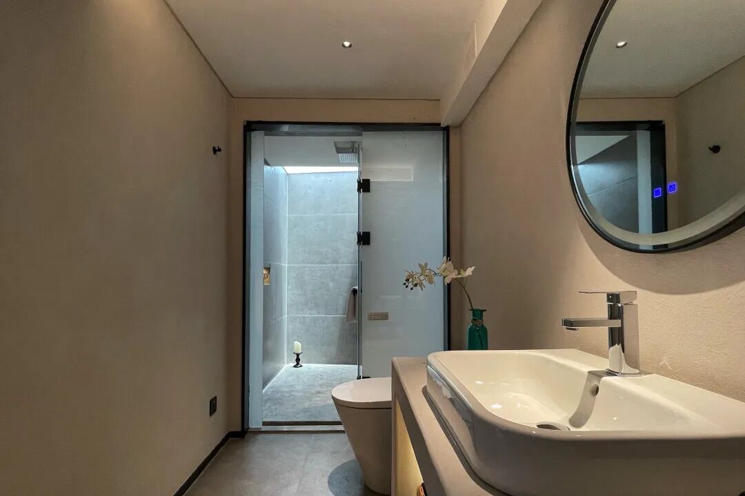 Un baño moderno con un lavabo grande, inodoro y cabina de ducha con mampara de vidrio.