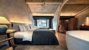 A modern bedroom with a large bed, bedside tables, a chair, and a bathtub. - Phoenix Hall House Hotel (Xiangxi)