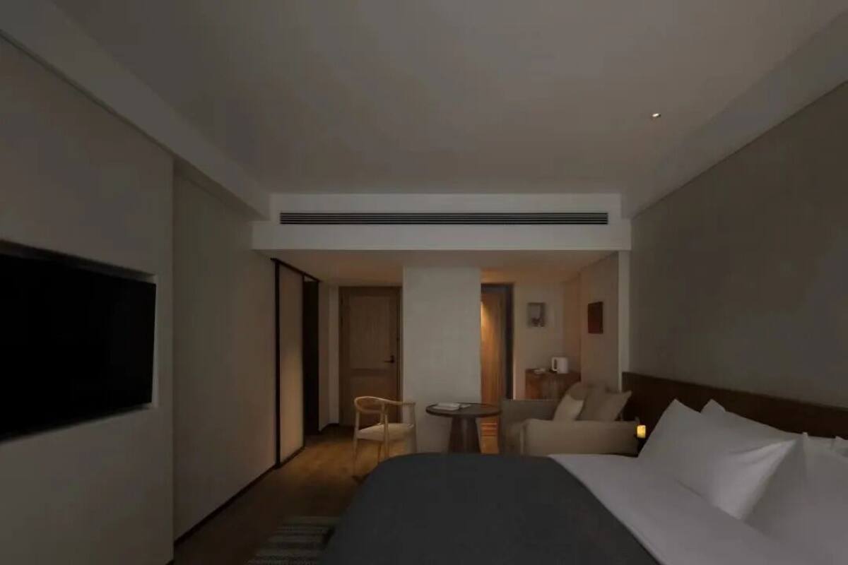 A hotel room with a bed, a desk, a chair, and a television.