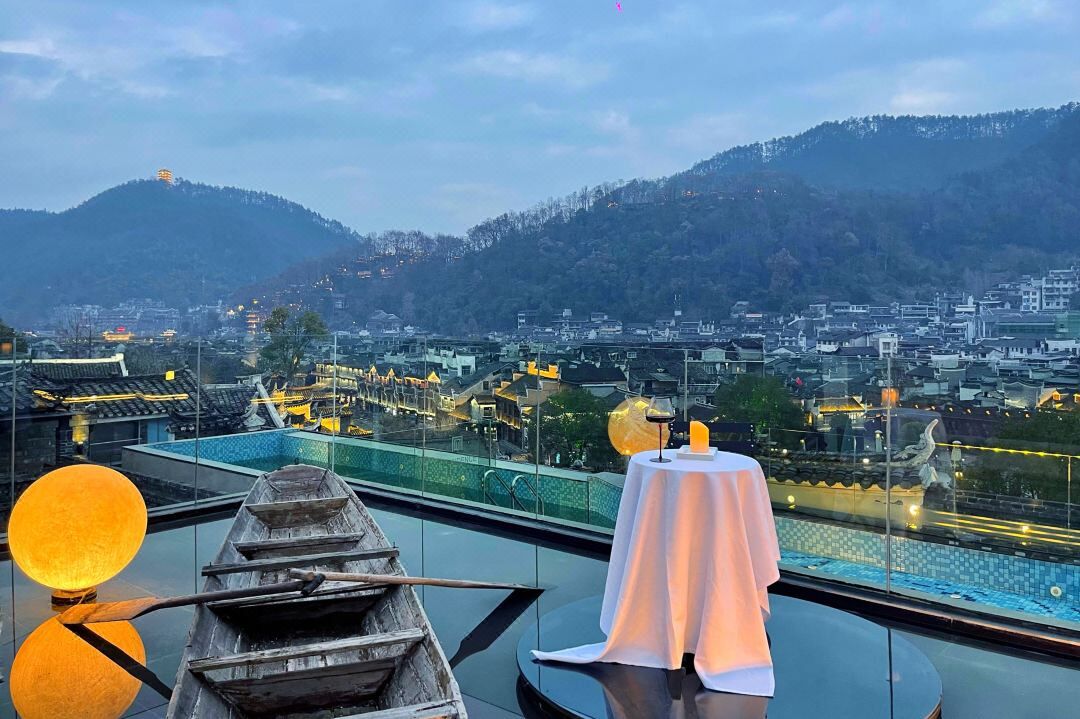 A rooftop terrace with a view of a cityscape and mountains.