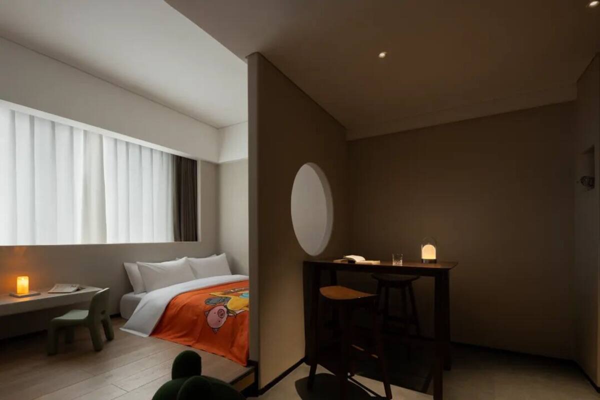 A modern hotel room with a bed, a desk, and a chair.